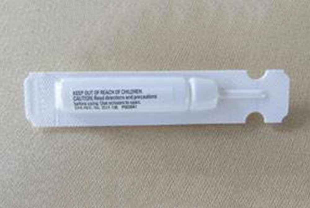 A single, small plastic tube or container with a white label is placed on a beige surface. The label includes text that cautions to keep it out of reach of children, followed by additional instructions and warnings in small print that might be familiar to any veterinarian or vet technician.